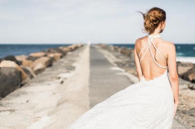 Жена в сватбена рокля на брега на морето
