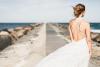 Жена в сватбена рокля на брега на морето